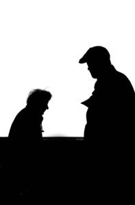 High contrast silhouette photo capturing two adults conversing against a white background.